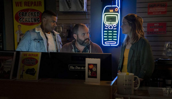 Jordan Calloway, Tom Segura and Elizabeth Lail stand behind a desk in a phone shop