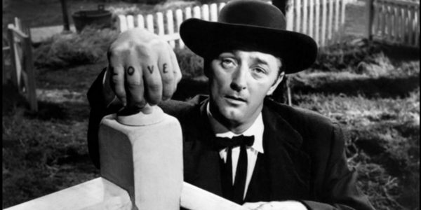 Robert Mitchum as Harry Powell leaning on a doorknob with the letters LOVE exposed on his knuckles