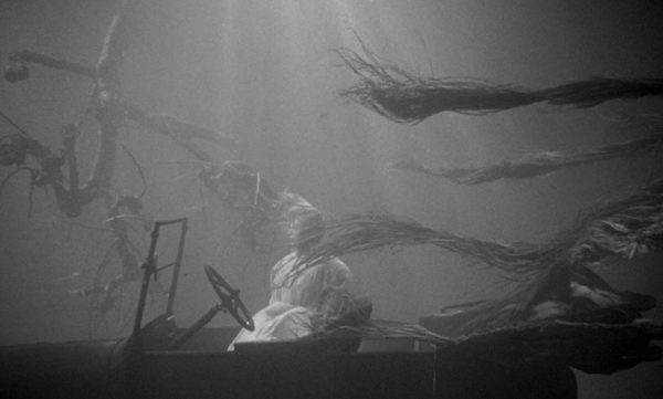 The corpse of a woman in a white dress tied to a car that is at the bottom of a lake
