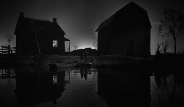 Black and white image of the sun rising in between two house