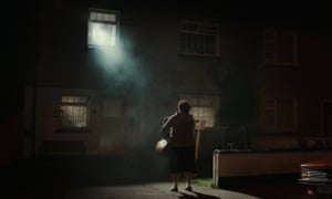 Maeve Higgins stands on the street in front of a lit window in homage to The Exorcist