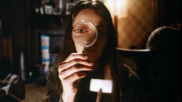 Linda (Jacki Kerin) holds a magnifying glass up to her face