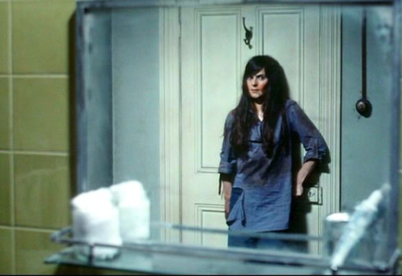 Linda (Jacki Kerin) looks at herself in the mirror as she presses up against the bathroom door, bloodies and desperate