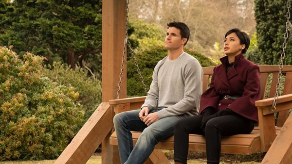 Nathan (Robbie Amell) and Nora (Andy Allo) sit on a bench outside