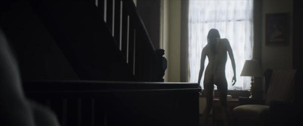 A naked woman stands crookedly in front of a window