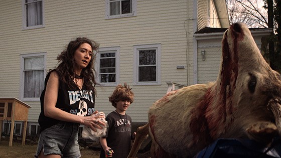 Zarah Mahler as Abby and Blane Crockarell as Dillon stare at the dead body of a buck in the back of a truck