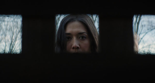 Abby (Zarah Mahler)'s face is framed in a square as she stares into the cellar