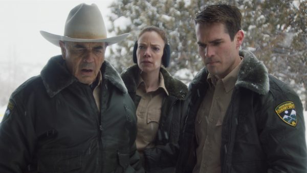 Three police officers stare at a something grisly on the ground