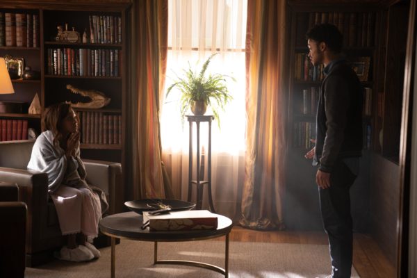 A College aged man stands in front of a woman seated on a couch