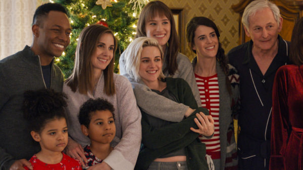 A mixed race family poses in front of a Christmas tree