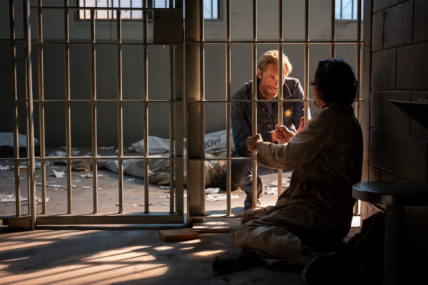 Alexander Skarsgård as Randall Flagg kneels in front of a prison cell