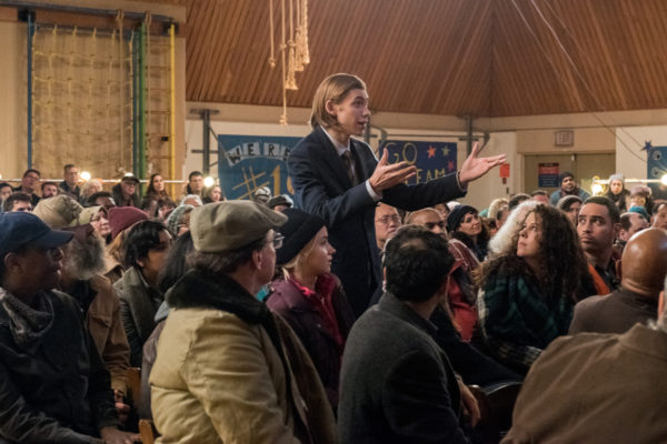 A young man in a suit addresses a crowd