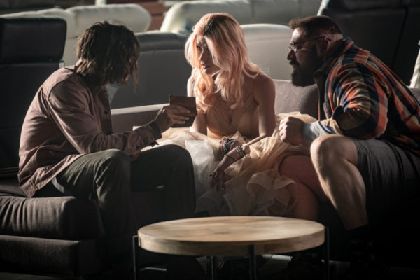 A pink haired woman in a prom dress sits in between two men