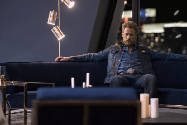 A blonde man in denim sits on a couch