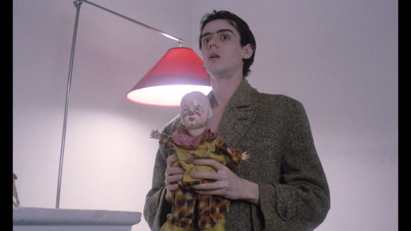 A young man in a wool coat clutches a doll