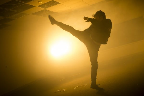 A yellow back lit illuminates a man kicking