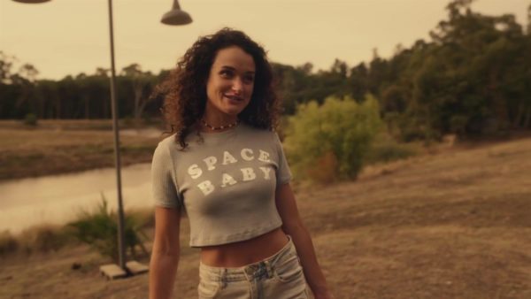 A girl with curly brown hair wearing a Space Baby crop top shirt