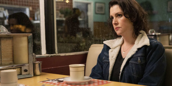 A brunette sits at a diner table