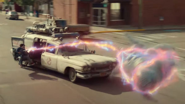 A white station wagon pursues a ghost caught in a beam of light down the street