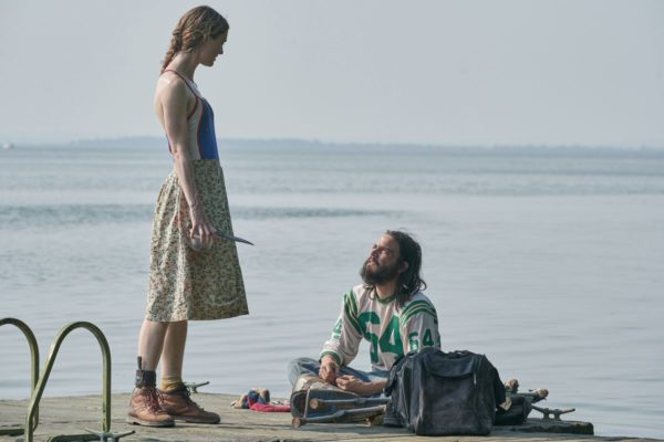 A woman holding a knife stands above a seated man at the end of a dock