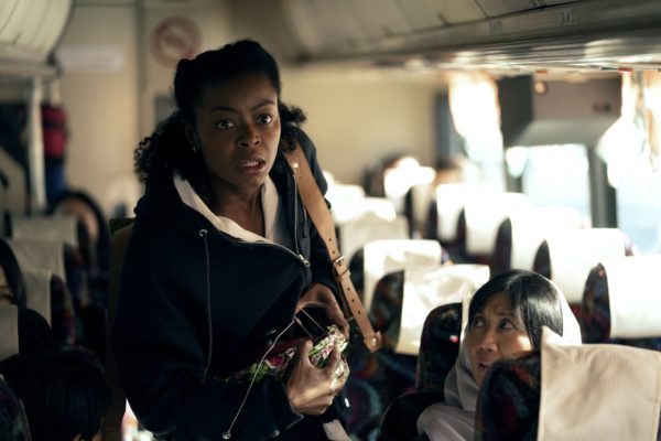 A black woman stands on a crowded bus