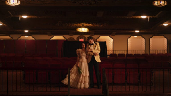 A man and woman in wedding attire stands in a theatre