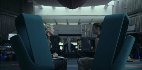 Two women conversing while seated on airport chairs