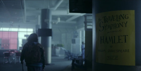 A man walks away from a sign advertising a performance of Macbeth