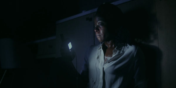 A woman speaks on the phone in a dark hotel room