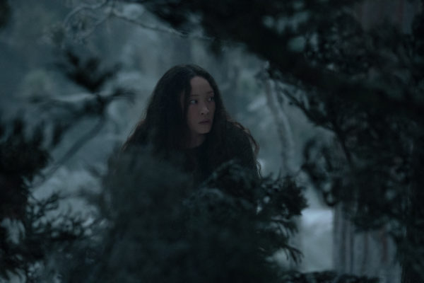 A woman crouches in the snowy woods