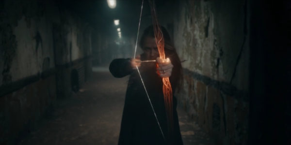 A blonde woman pulls back a magical bow and arrow
