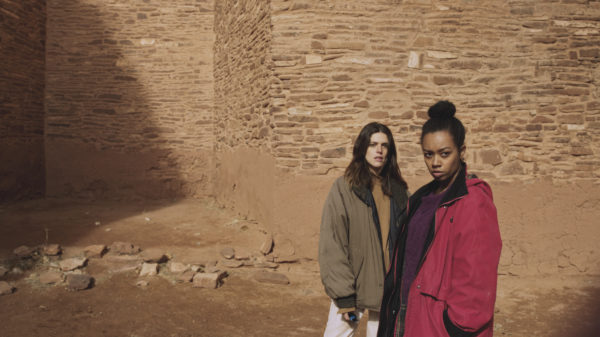 Two women stands in front of a rock wall