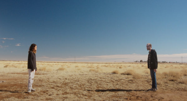 A woman (L) stares down a man (R) in the desert
