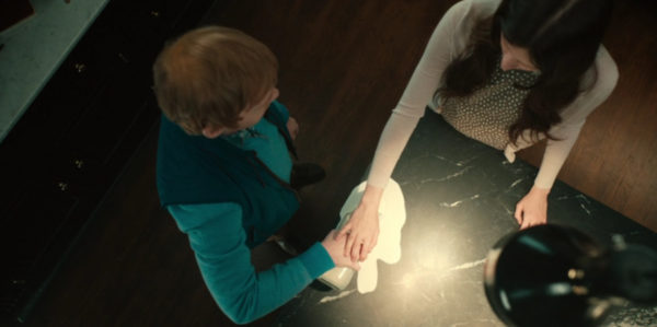 An overhead shot of a man over filling a glass of milk