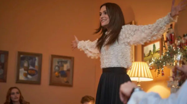 A brunette woman stands with her arms open