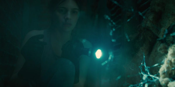 A woman shining a flashlight on a skeleton in a blue lit tunnel