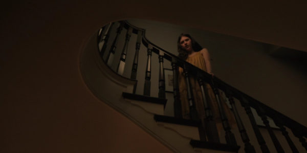 A dark haired woman standing on a flight of stairs