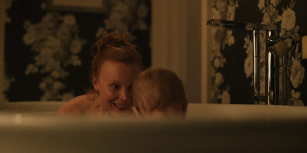 A red headed woman in the bath with a baby