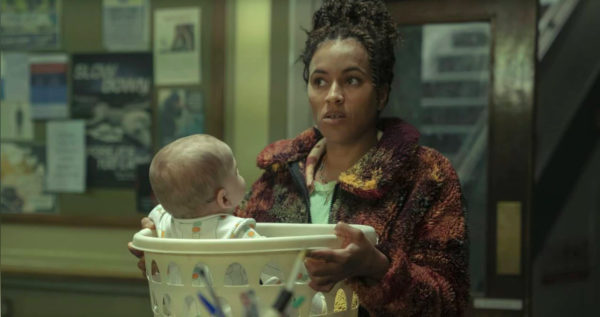 A woman places a baby in a laundry bin on a counter