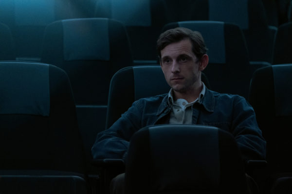 A young man sits in an auditorium