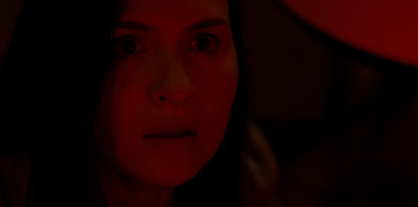 A close up of a woman's face bathed in red light