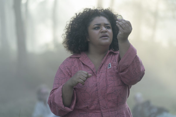 A black woman holds a coin in the air