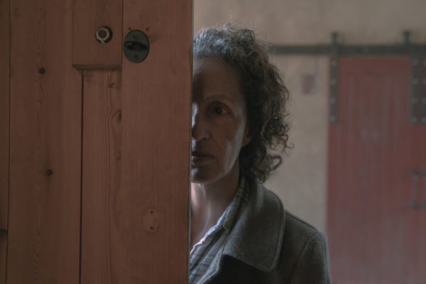 An old woman partially obscured by a door