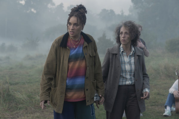 A middle aged woman (L) and an older woman (R) stand in a misty clearing