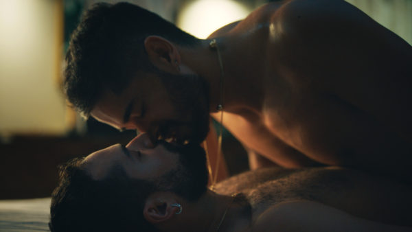 Two men kissing shirtless in bed