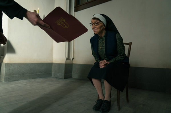A seated nun looking at a book