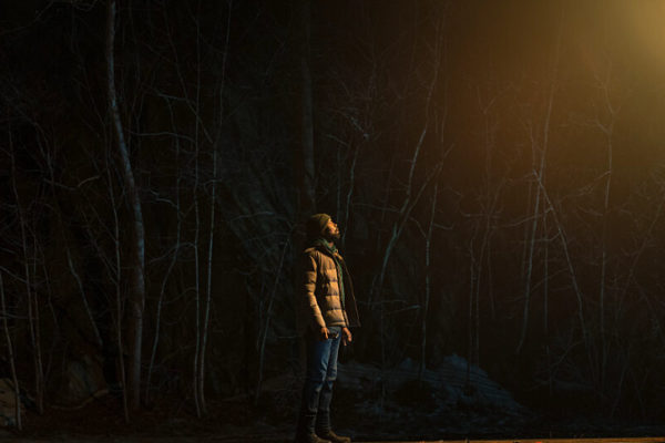 A black man staring at a light in the sky