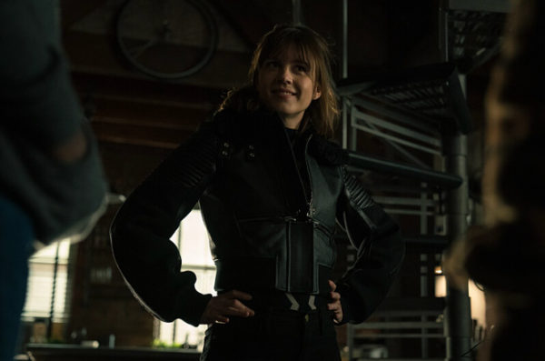 A brunette woman posing confidently in a leather jacket