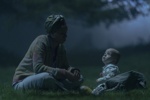 A woman sits with a baby in a field at night