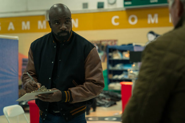 A black man holding a clipboard in a gymnasium